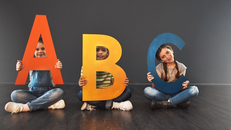 Barn sitter med bokstäverna ABC i knäet
