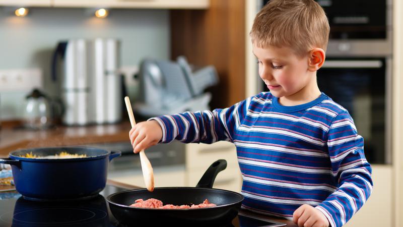 Ett barn steker mat i stekpanna
