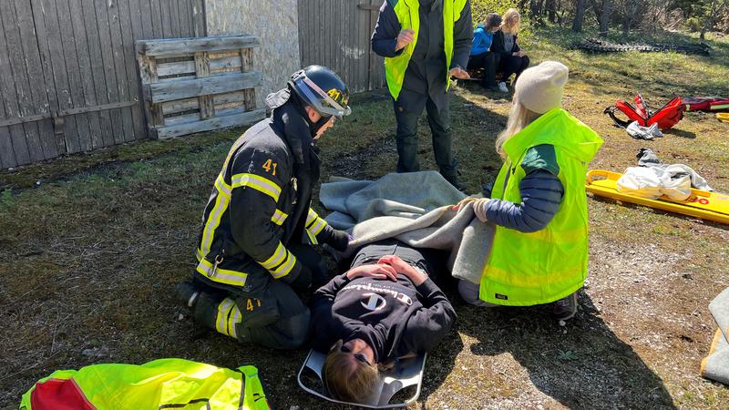 En person ligger på marken och blir omhändertagen av tre personer på en uppsamlingsplats vid en övning.uppsamlingsplats för skadade på skadeplatskurs 