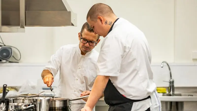 Kocklärare instruerar elev i ett kök.