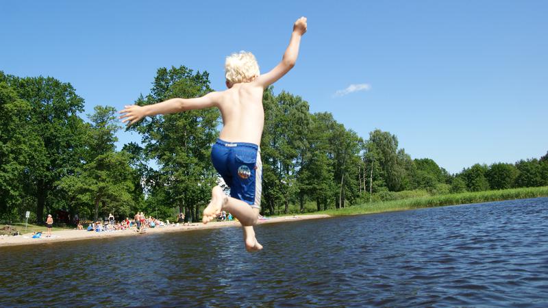 Barn som hoppar i vattnet från en brygga