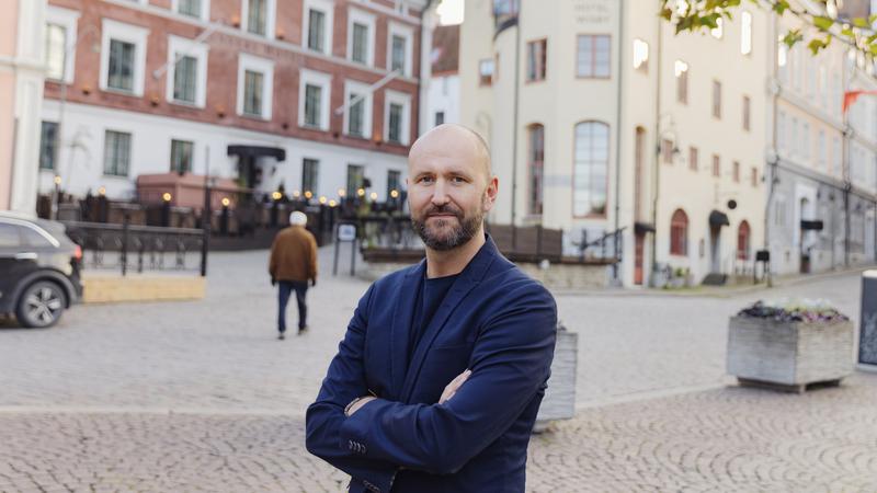 En man står på torget Donners plats i Visby med korslagda armar och tittar in i kameran. 