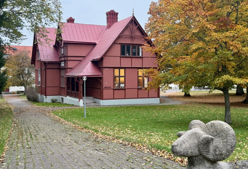 Ett hus med rött tak och en staty i sten framför.