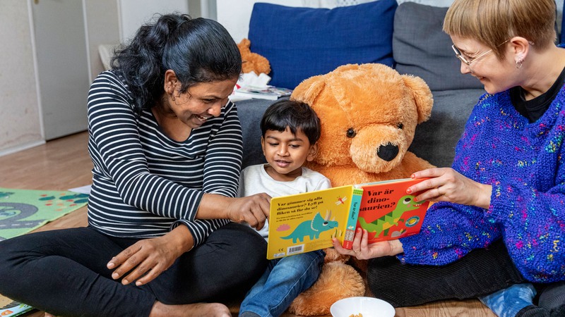 Kvinna och barn i hemmamiljö läser ur en bok tillsammans under ett bokstartsbesök.