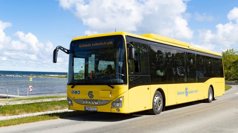Gul buss som kör på landsväg med hav och blå himmel i bakgrunden