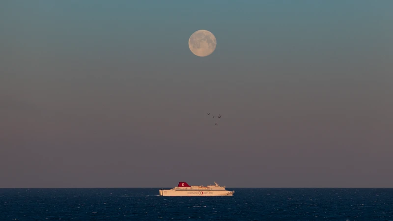 En båt på havet med fullmånen i bakgrunden.