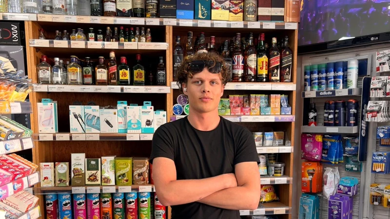 En man som står bakom disken i en butik.