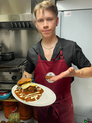 En person som håller en tallrik med mat i ett kök.