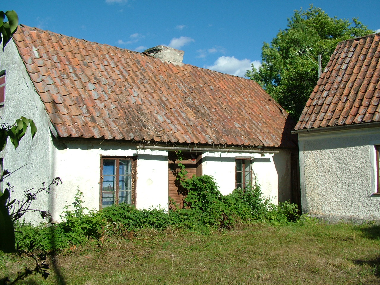 Två vita hus med bruna fönster, bruna dörrar och bruna tak med skorstenar.