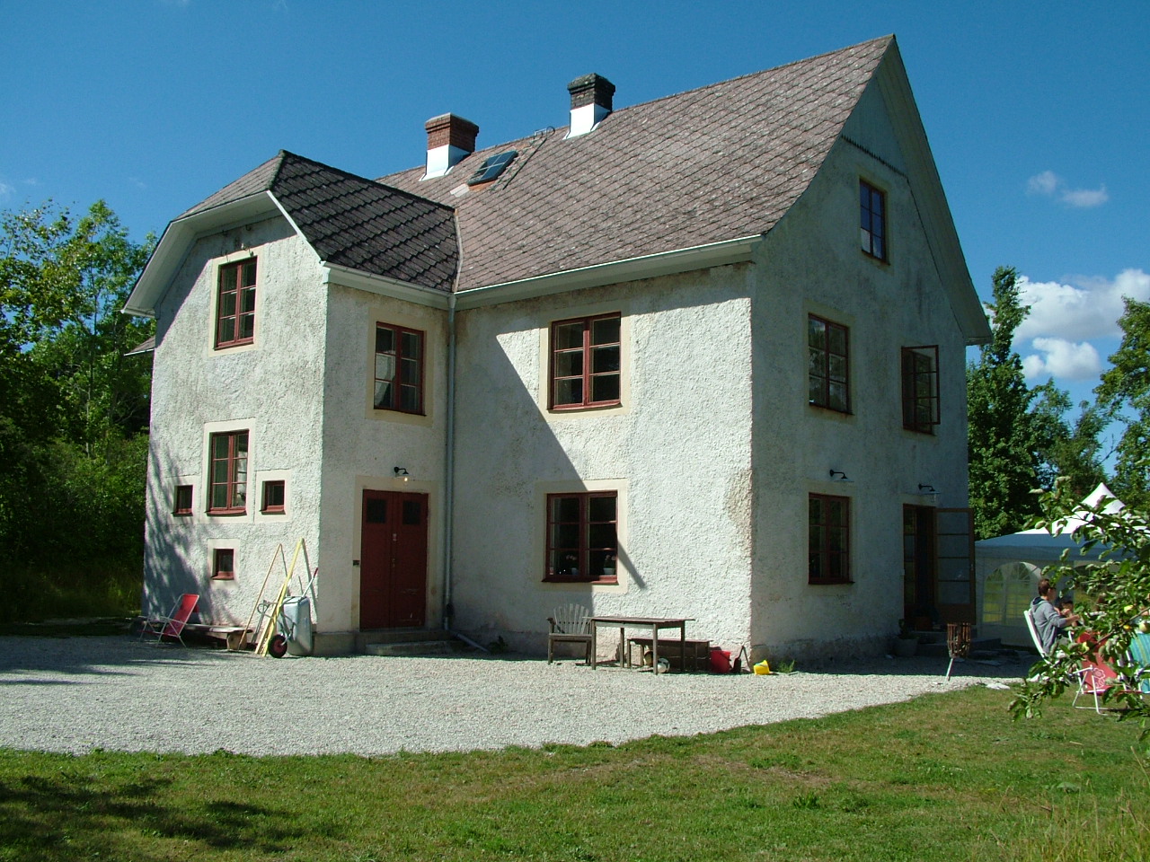 Ett stort vitt hus med bruna fönster, bruna dörrar och ett brunt tak med en skorsten.