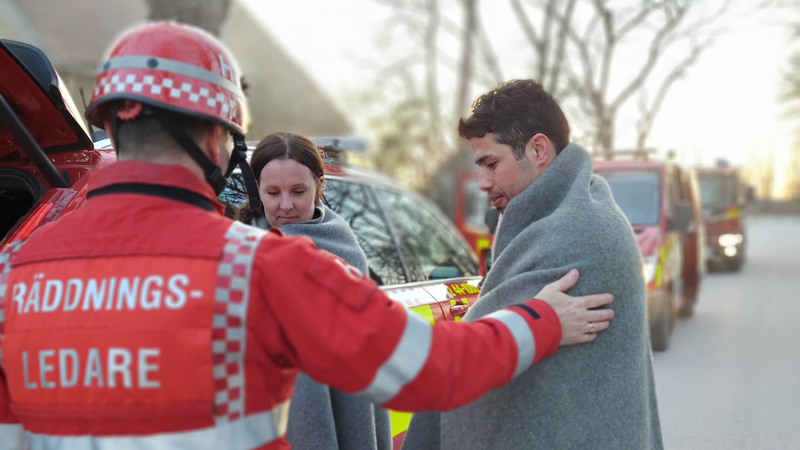 Räddningsledare tar hand om två personer vid en bil