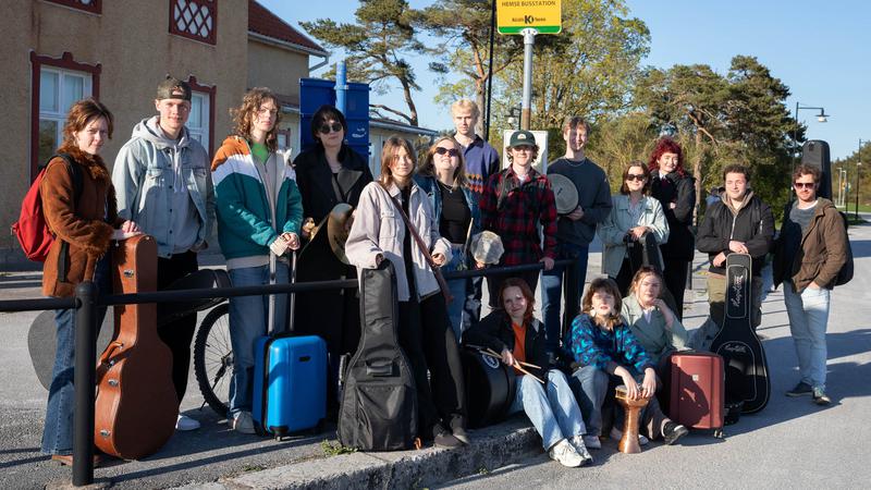 Elever på Gotlands folkhögskolas musiklinjer står vid en busshållsplats.