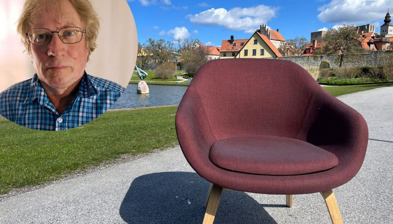 Ett foto av en man med glasögon bredvid en stol.