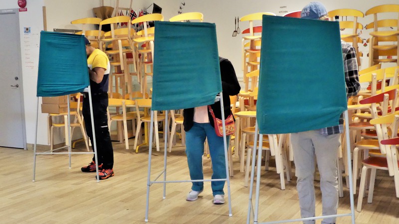 Tre personer står i varsitt röstbås.