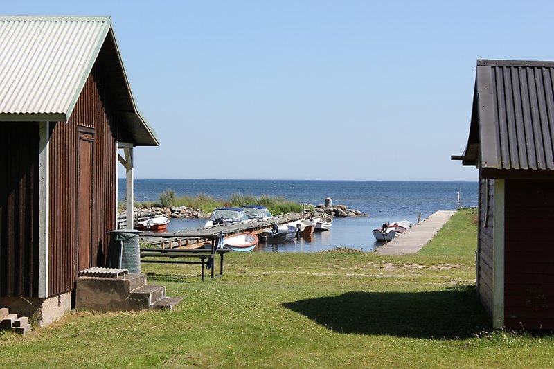 Två fiskebodar vid vattnet och flera små motorbåtar är parkerade längs hamnen.