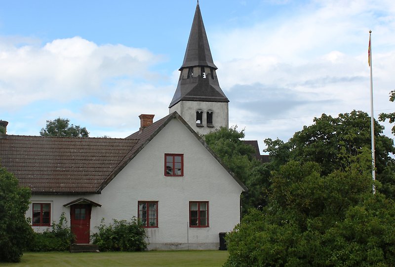 Anga kyrka syns bakom en vit byggnad.