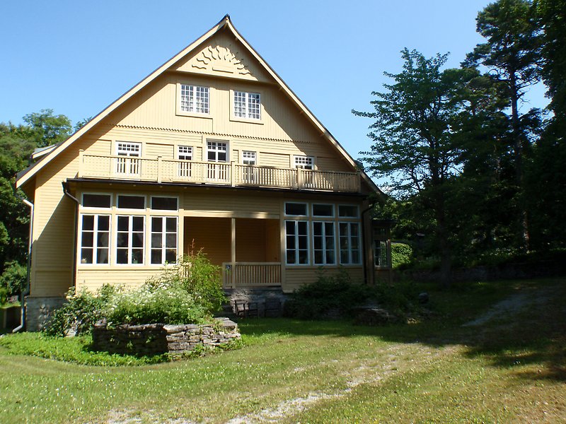 Gaveln på ett stort hus med gul fasad och vita fönster.