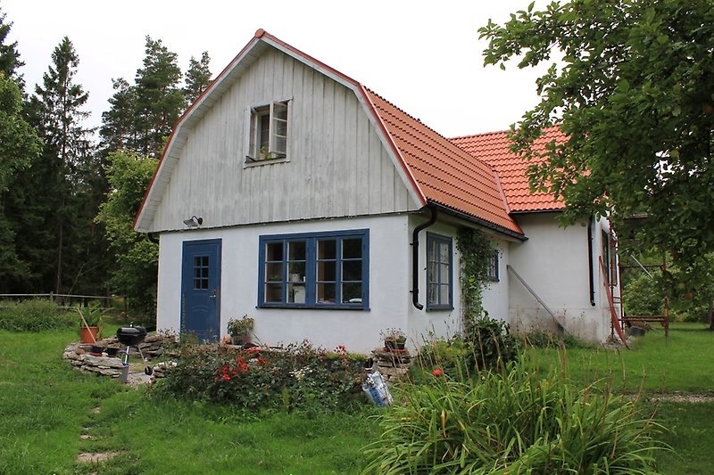 Ett vitt hus med blåa fönster, en blå ytterdörr och ett rött tak.