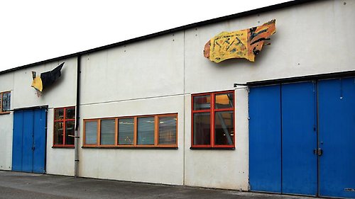 En låg byggnad med blåa portar och märkliga föremål på väggen