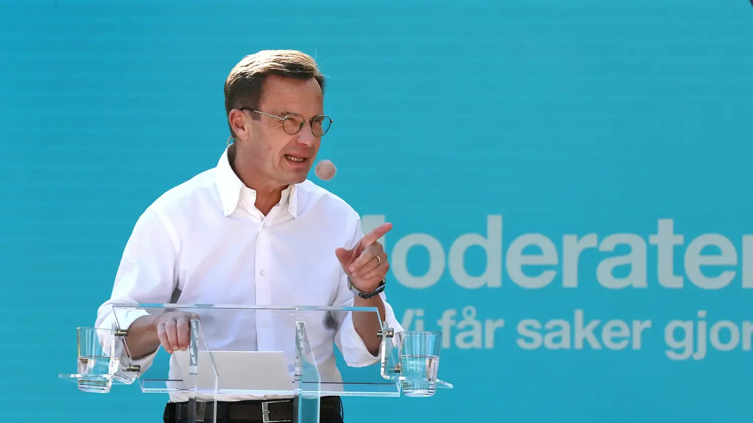 Ulf Kristersson bakom en genomskinlig talarstol med texten moderaterna i bakgrunden