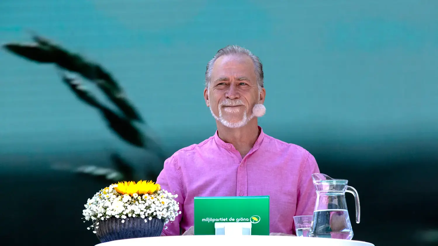 Daniel Helldén bakom en talarstol med en blomma