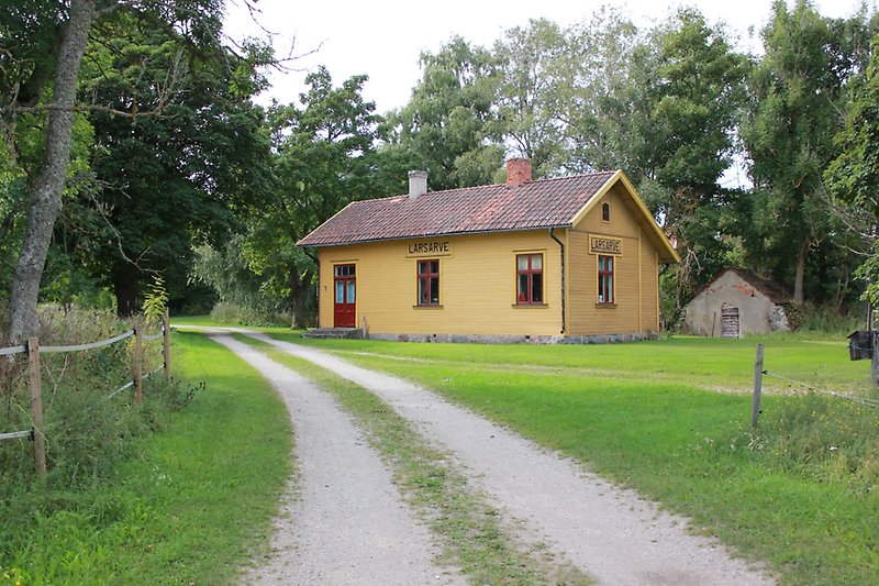 Ett litet hus med gula träväggar, röda fönster, röda dörrar och ett rött tegeltak.