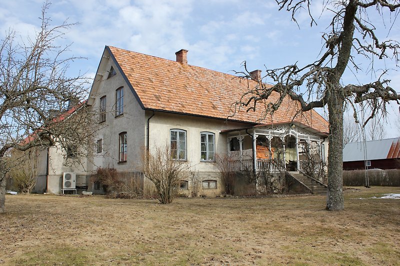 Ett tvåvåningshus med gråa fönster och ett orange tegeltak med två skorstenar.