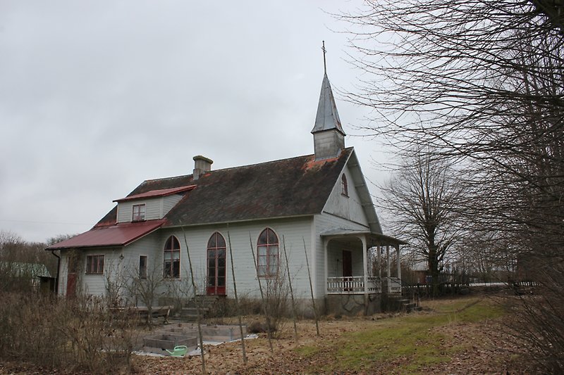 Kapellet i Alva är en byggnad med röda fönster, med en ljusblå träfasad och ett svartrött tak.