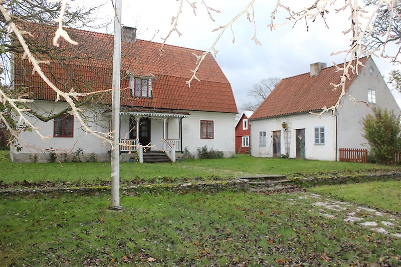 Två vita hus med rött tegeltak och grön gräsmatta.