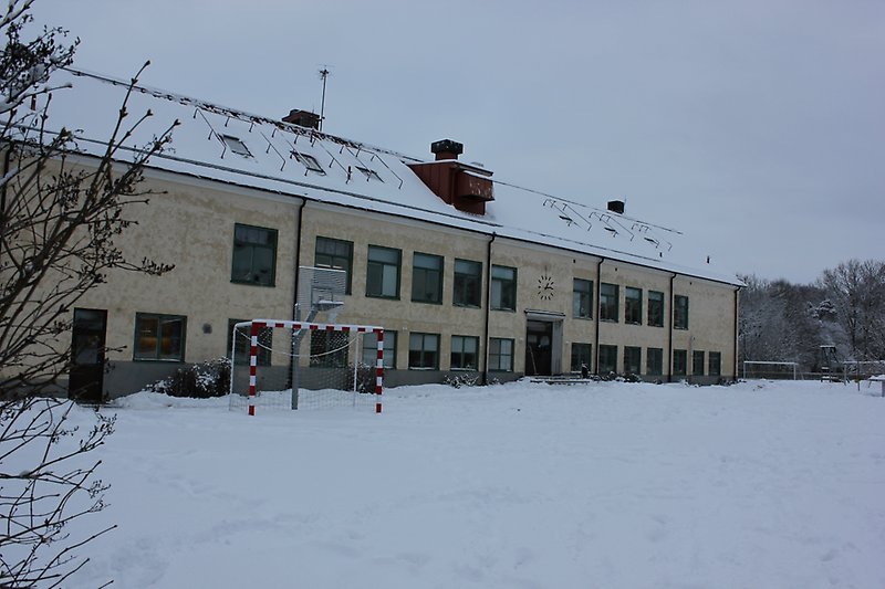 Havdhems grundskolans byggnad består av två våningar med gröna fönster, gröna dörrar och ett rött plåttak.