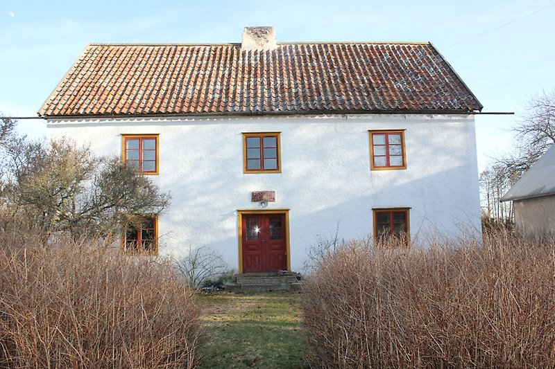 Ett vitt hus med röda dörrar och gula dörrkarmar samt röda fönster och gula fönsterramar.