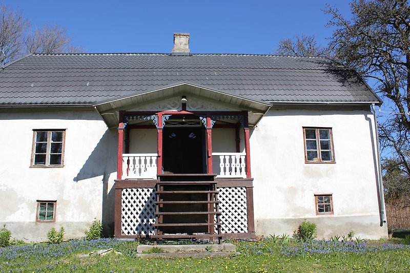 Ett vitt hus med bruna fönster och ett svart plåttak med en skorsten.