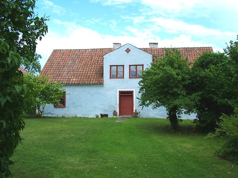 Ett vitt hus med bruna fönster, ett brunt tak och en brun ytterdörr.