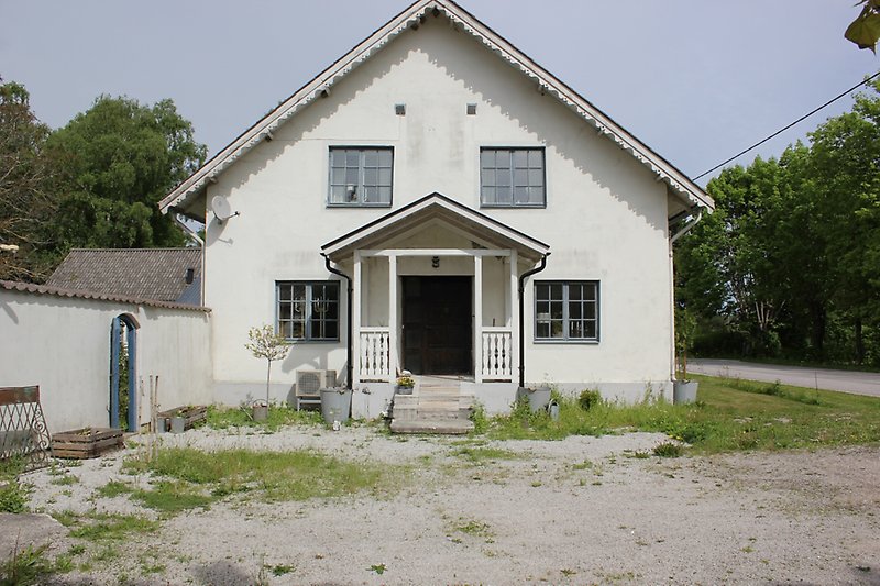 Gaveln på ett vitt hus med gråa fönster och ett svart ytterdörr.