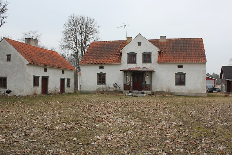 Två vita hus med brungröna fönster samt dörrar och orange tak med skorstenar.