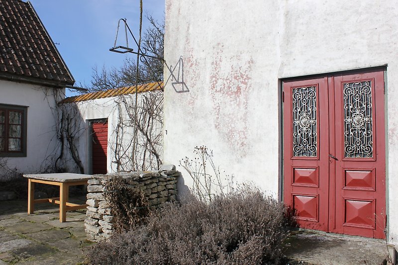 En vit byggnad med putsade väggar och röda dörrar.