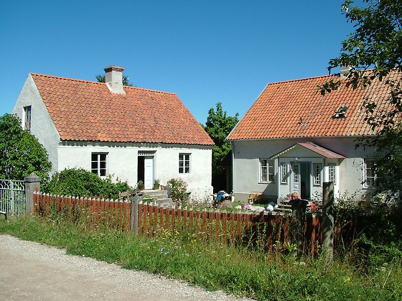 Två små vita hus med vita dörrar, vita fönster och röda tak med skorstenar.