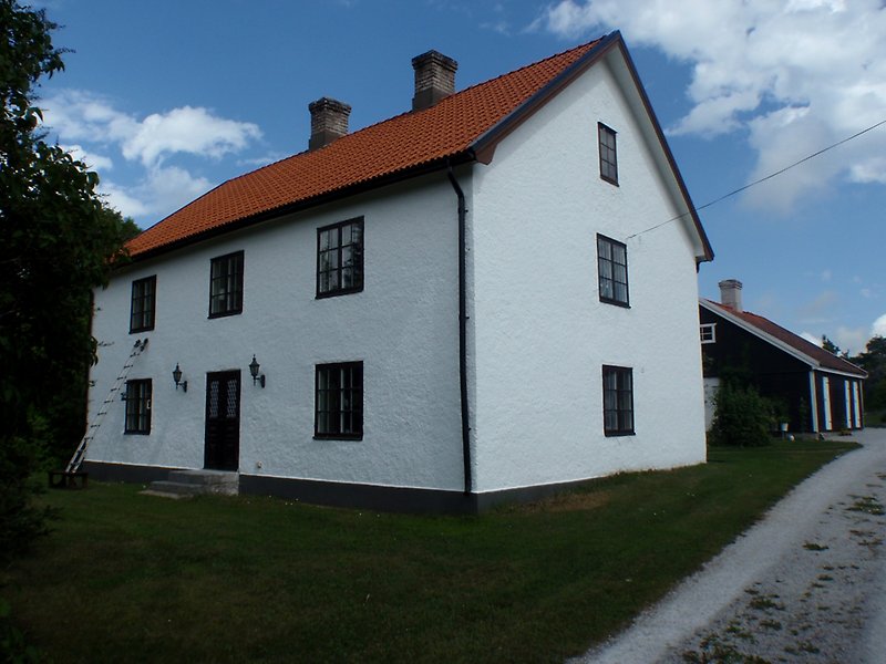 Ett vitt tvåvånings hus med två skorstenar och ett rött tak.