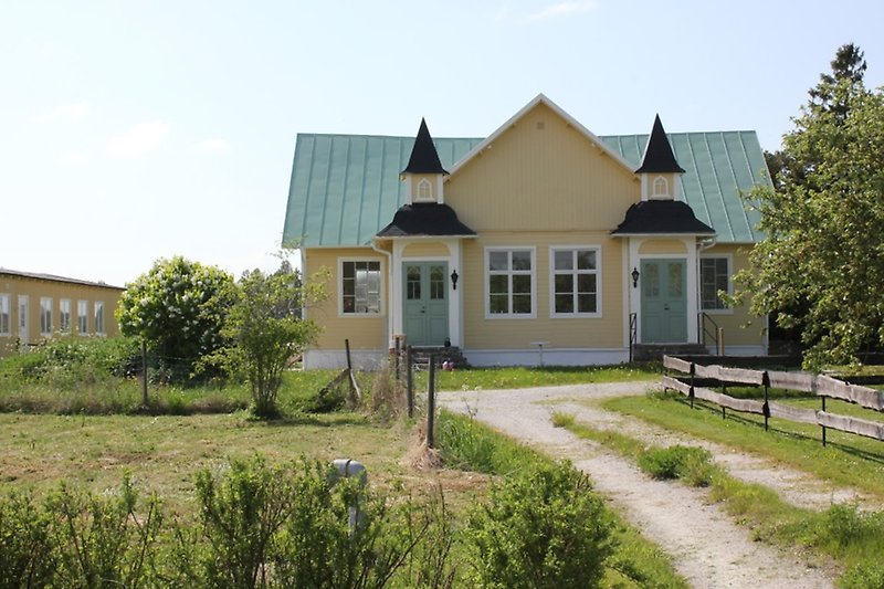 Ett sagolikt hus med gula väggar och ett grönt tak.