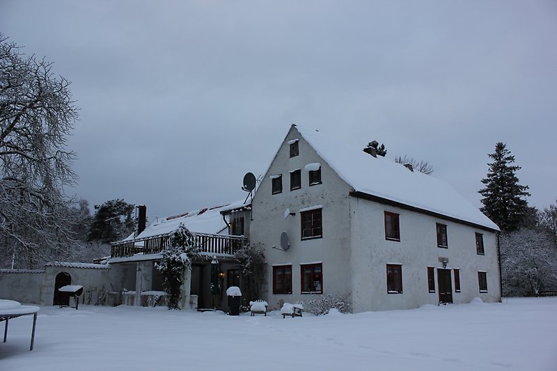 Ett vitt hus av tre våningar under vintertid.