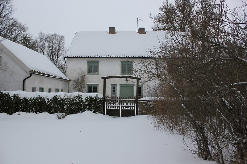 Två vita hus med gröna fönster och med en lite snö på taket.