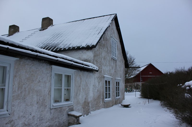 Ett vitt hus med vita fönster och ett svart plåttak.