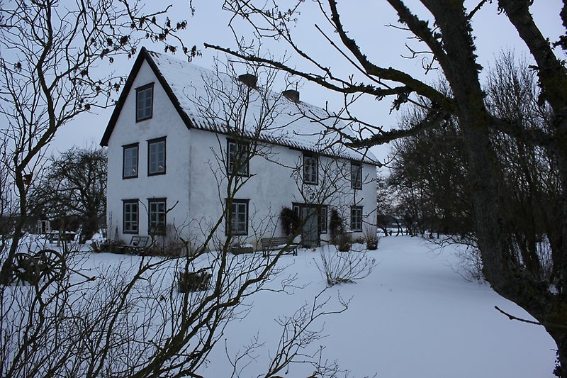 Ett vitt hus med gråa fönster och ett svart plåttak.