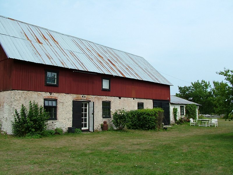 Rödvit byggnad med plåttak och grön gräsmatta