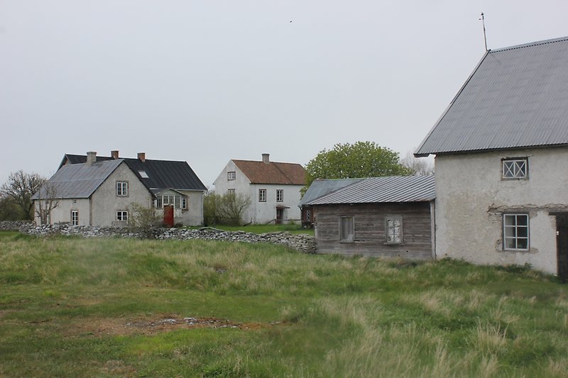 Byggnadsområdet bestående av flera vitgråa hus på landet.