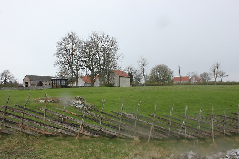 Ett grönt fält med ett staket och några små byggnader.