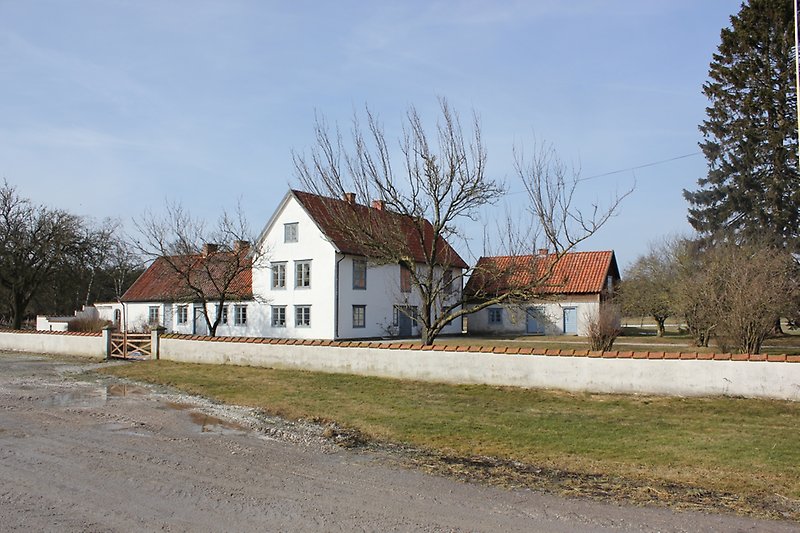 Ett stort vitt hus med gråa fönster och ett rött tak.