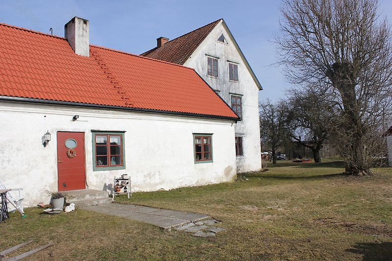 Två vita hus med bruna fönster, gröna fönsterramar och röda tak.