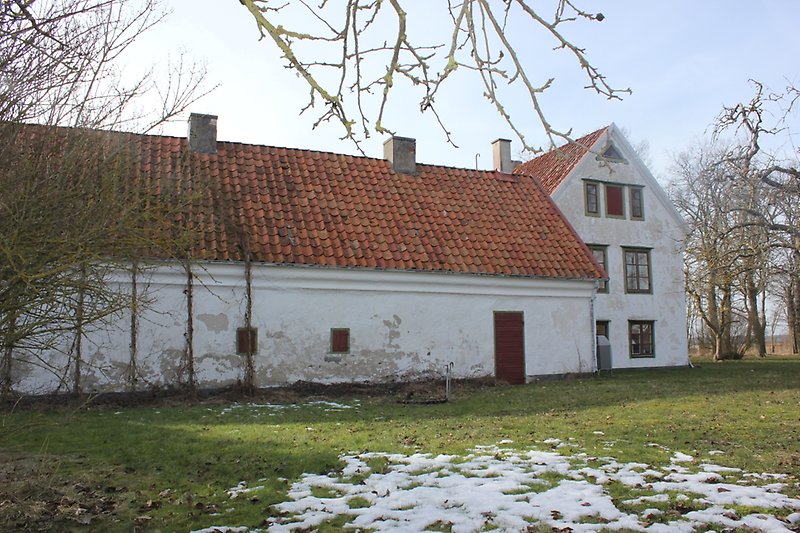 Ett vitt hus och ett vitt gårdshus med orange tak och flera skorstenar.