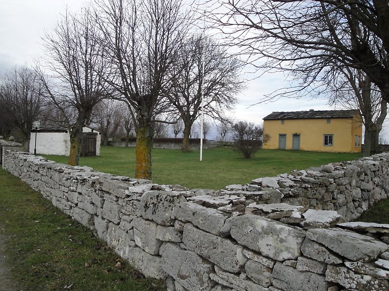En kyrkogård med flera byggnader och en stenmur.